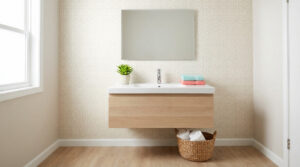 A clean, modern bathroom vanity with a light wood cabinet, white basin, chrome faucet, succulent, and colorful towels. Light patterned wallpaper and wood-toned floor.